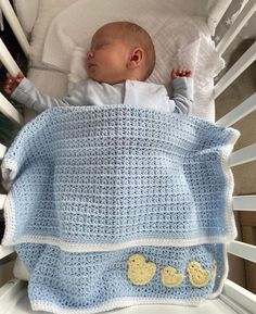 a baby laying in a crib with a blanket over it's head and two rubber ducks on the bottom