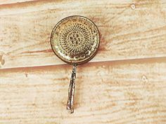 a small metal object is hanging on a wooden surface with wood planks in the background