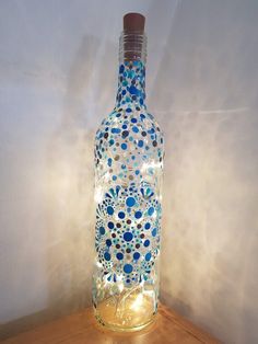 a bottle that has been decorated with blue and white dots on it, sitting on a wooden table