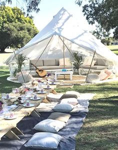 a tent set up for a picnic with pillows and plates laid out on the ground