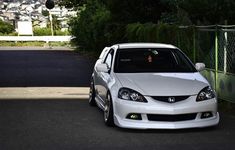 a white car parked in front of a fence