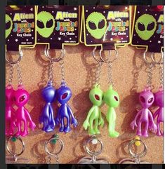 several alien key chains hanging on a wall