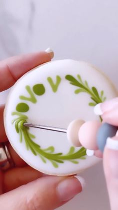 a woman is holding a green and white button with two pins in it's center