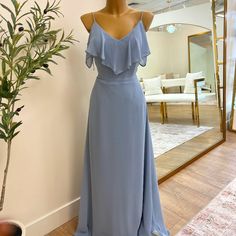 a dress is displayed on a mannequin in front of a mirror with a potted plant