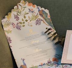 the wedding stationery is decorated with flowers and peacocks, along with an envelope