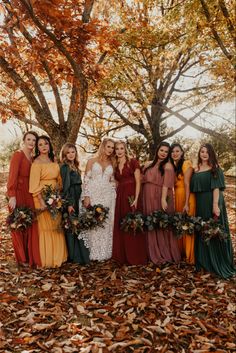 a group of women standing next to each other in front of trees with leaves on the ground