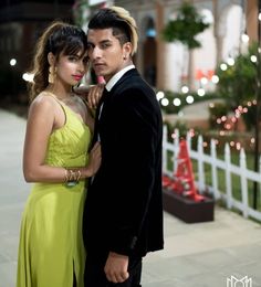 a man in a tuxedo standing next to a woman wearing a yellow dress