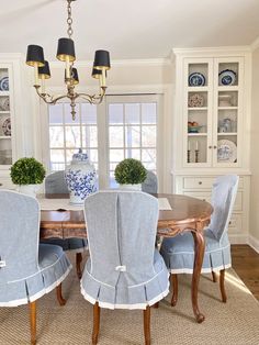 a dinning room table with blue chairs and white china cabinet in the back ground