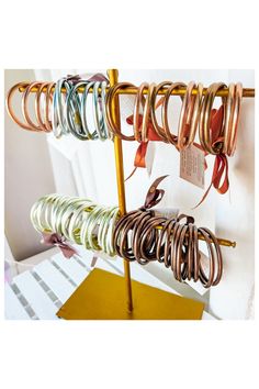 there are many different colored bracelets hanging on the rack with price tags attached to them