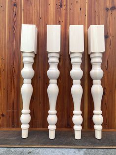 three white candlesticks are lined up against a wooden wall