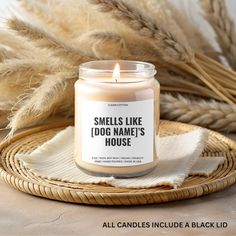 a candle sitting on top of a wicker basket next to some dry grass and pamy stalks