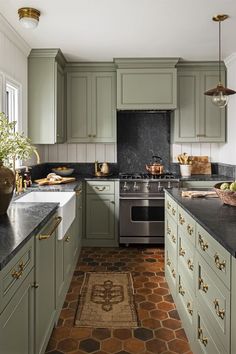 an image of a kitchen setting with green cabinets and black counter tops, including a stove