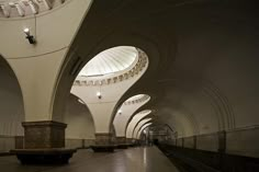 the inside of a subway station with many arches and lights on it's ceiling