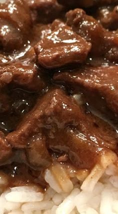 a close up view of some rice and meat on a plate with gravy