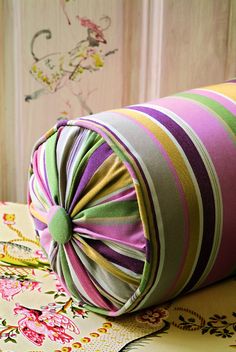 a roll of colorful fabric sitting on top of a table next to a floral wallpaper