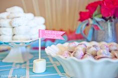 a table topped with white and pink candy covered in marshmallows next to a plate of cookies