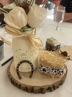 a vase filled with white flowers sitting on top of a wooden slice covered in hay