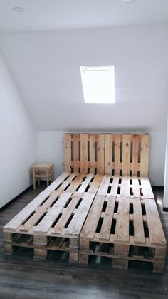 a bed made out of wooden pallets in a room with white walls and wood floors