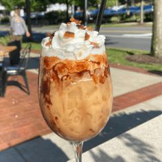 a glass filled with ice cream sitting on top of a table next to a sidewalk