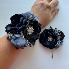 two blue flower bracelets on a woman's arm, one with silver and black flowers