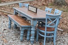 a blue table and four chairs with a sign on it sitting in the middle of gravel