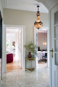 an open door leading to a bedroom and living room with a chandelier hanging from the ceiling