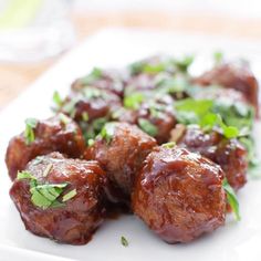 some meatballs are on a white plate with garnishes and parsley