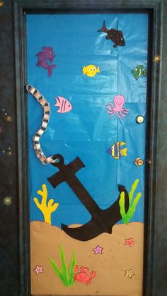 a door decorated with an anchor, fish and seaweed in the sand under water