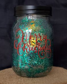 a green and red christmas jar sitting on top of a burlock covered table