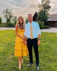 a man and woman are standing in the grass holding hands while smiling at the camera