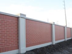 a red brick wall next to a white fence