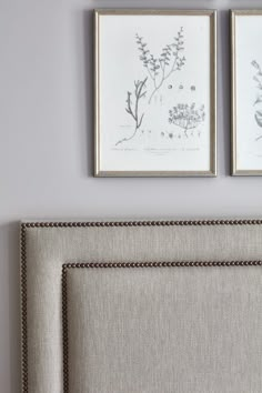 two framed pictures hang on the wall above a bed with linen headboard and foot board