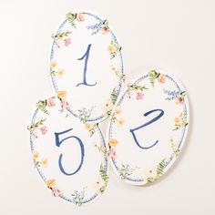 three floral plates with the number five on them and one has blue numbers in it