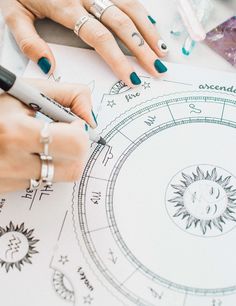 two hands on top of a paper with rings and pen in front of the drawing