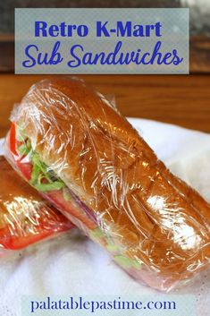 two sandwiches wrapped in plastic sitting on top of a white paper towel with the words retro k - mart sub sandwiches