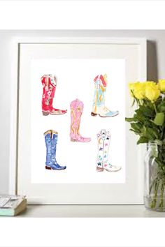 a vase with yellow roses and flowers in it next to a white framed print of cowboy boots