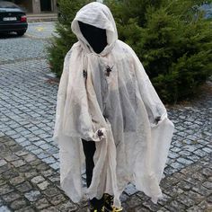 a person in a white ponchy with yellow shoes standing on cobblestone street