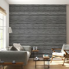 a living room with black and white striped wallpaper in the corner, two couches and coffee table