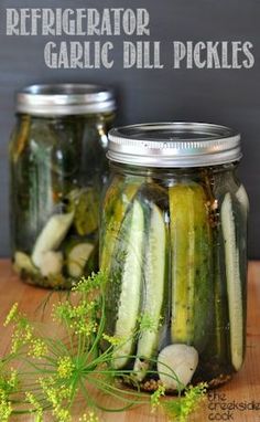 two jars filled with pickles sitting on top of a wooden table