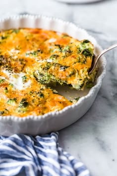 a casserole dish with broccoli and cheese in it on a marble table