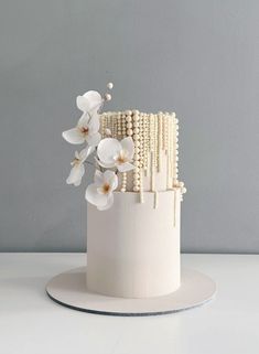 a white cake with pearls and flowers on top