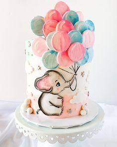 a cake decorated with balloons on top of a white plate and serving platter in the shape of an elephant