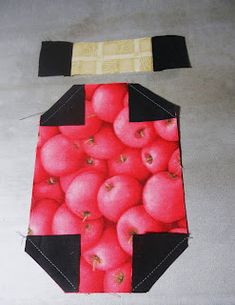 an origami piece with red apples in the middle and black squares around it