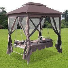 an outdoor bed with mosquito netting on top in the grass, next to a field