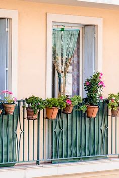 a balcony with potted plants and flowers on the balconies, next to an open window