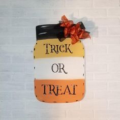 a painted mason jar that says trick or treat hanging on a brick wall with a bow