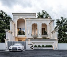 a white car is parked in front of a large building with arches and balconies