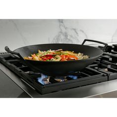 a wok is sitting on top of the stove with food in it's pan