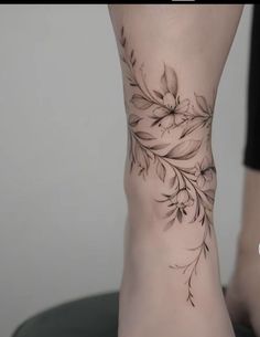 a woman's foot with flowers and leaves on the bottom part of her leg