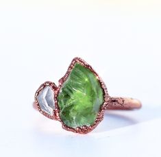 A bright green peridot is paired with a tiny Herkimer diamond in this warm and soothing heart chakra ring. Stones are set in copper on a pure, solid copper band. Herkimer diamonds are said to boost the energy of all other stones, so it is the perfect gem for a little pop of sparkle and energy in this powerful piece!   Turn your ring to gold or silver through the links below! ~GOLD~ https://www.etsy.com/listing/1492548887/ ~SILVER~ https://www.etsy.com/listing/1481946214/ This listing is for one Unique Green Rings With Rose Cut Diamonds, Green Peridot Rings With Nature-inspired Style, Green Jewelry With Rose Cut Diamonds For Gifts, Green Rose Cut Diamonds Jewelry As A Gift, Green Rose Cut Diamonds Jewelry Gift, Green Rose Cut Diamond Rings As A Gift, Chakra Ring, Ring Stones, Herkimer Diamond Ring